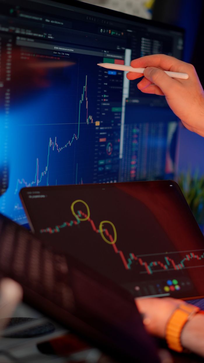 A person analyzes cryptocurrency market trends on multiple screens with graphs.